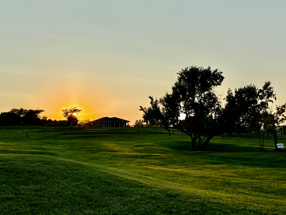 Golf course with sun rising in distance